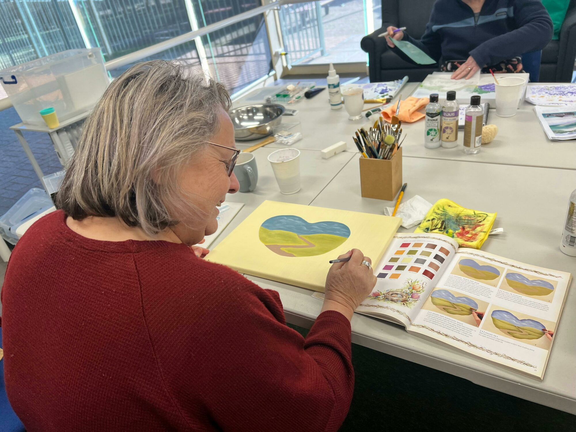 Participant painting, using a textbook for reference