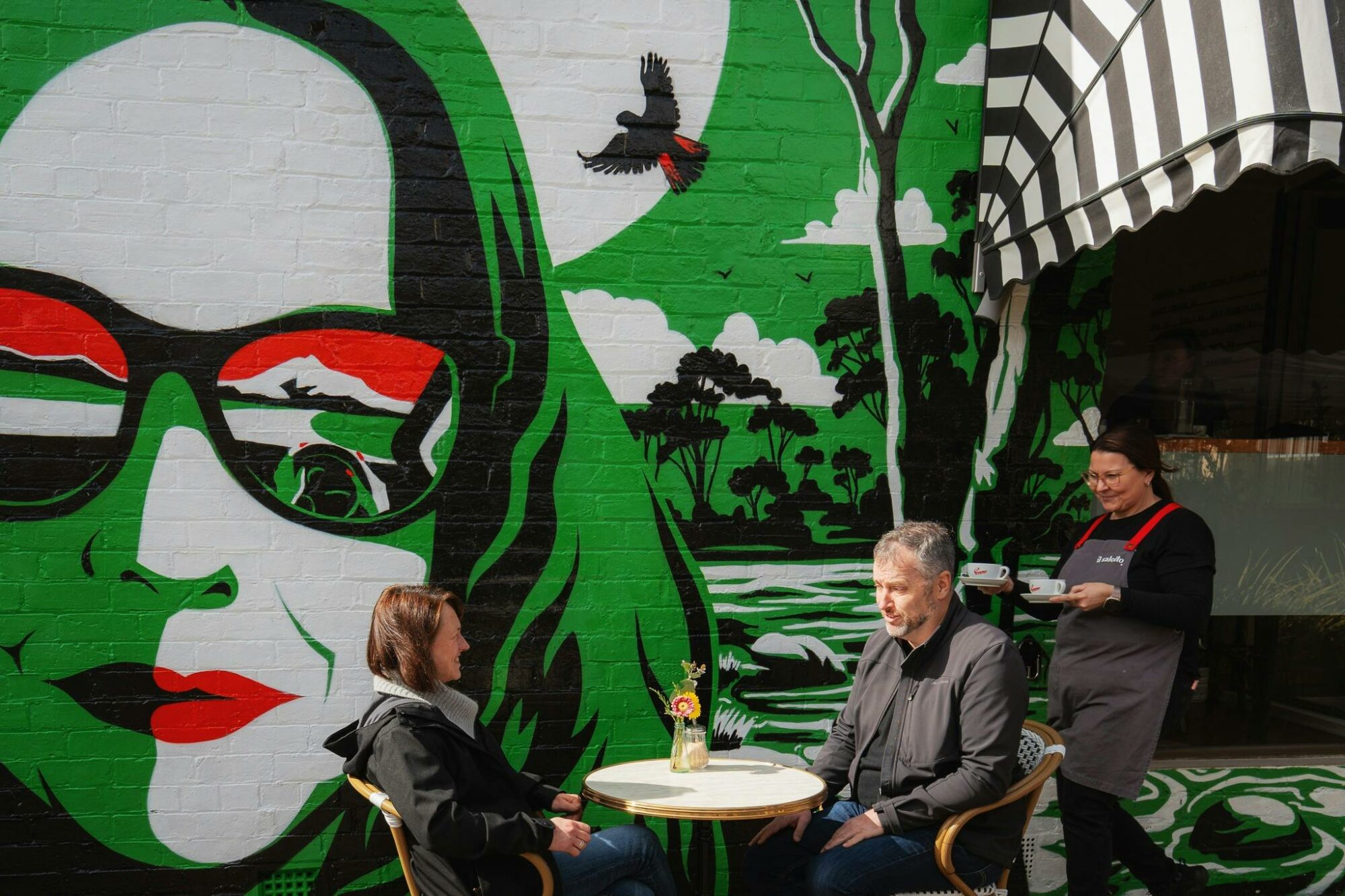 A mural with a woman with green hair and sunglasses with red, green, white and black in the frames