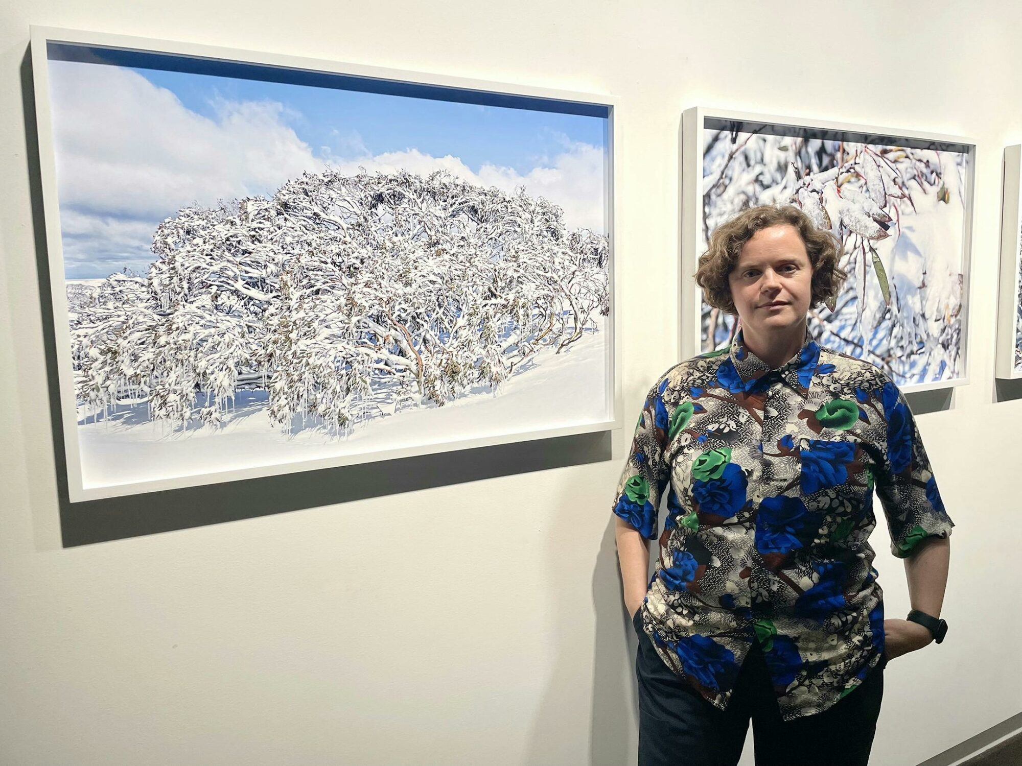 Artist Sarah Lynch standing in front of her photographic series  Above the Snow Line, Triptych 2