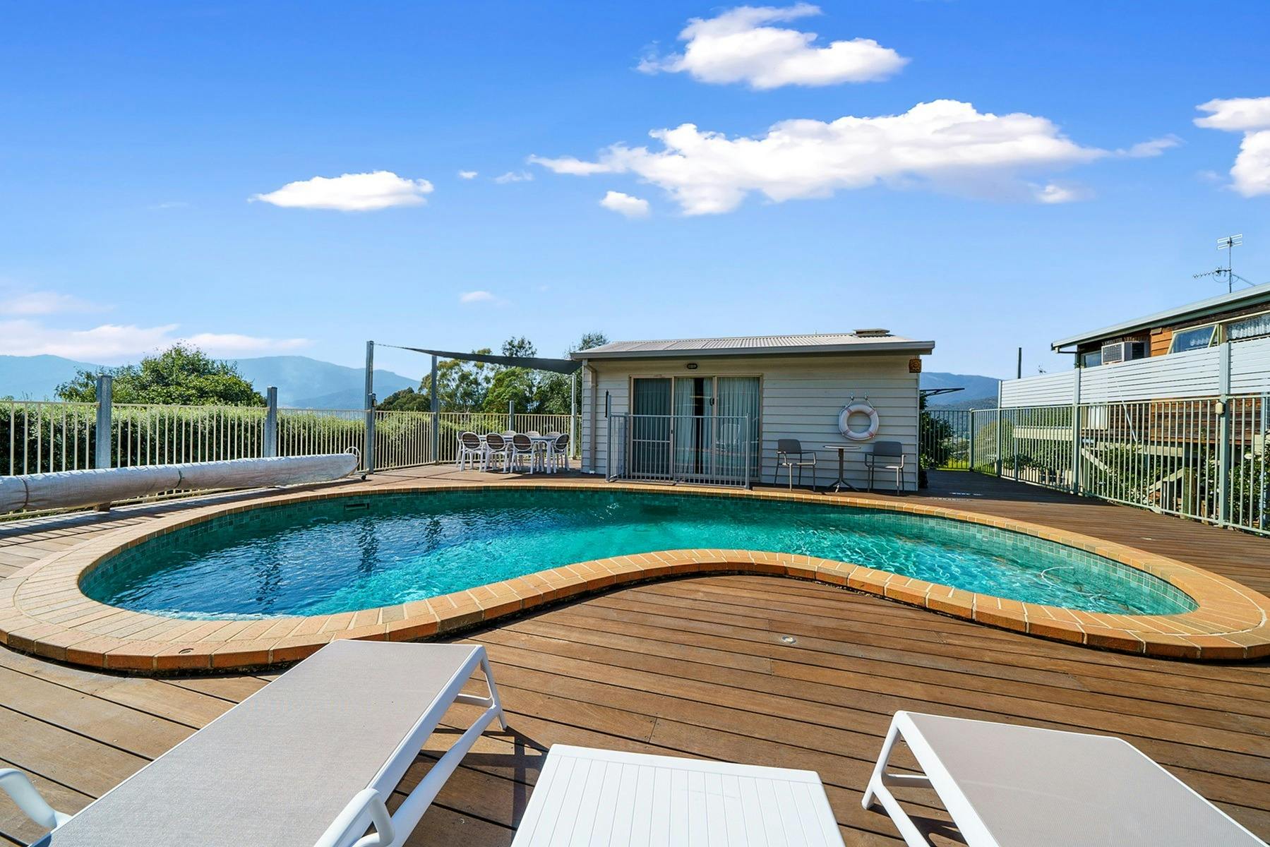 An outdoor swimming pool with decking and chairs around it