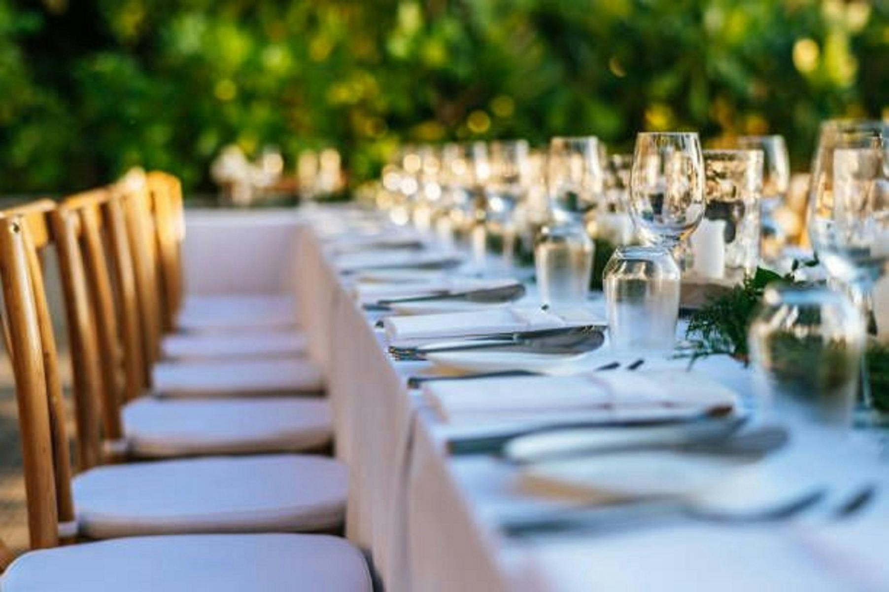 long table with white chairs set for a formal dinner