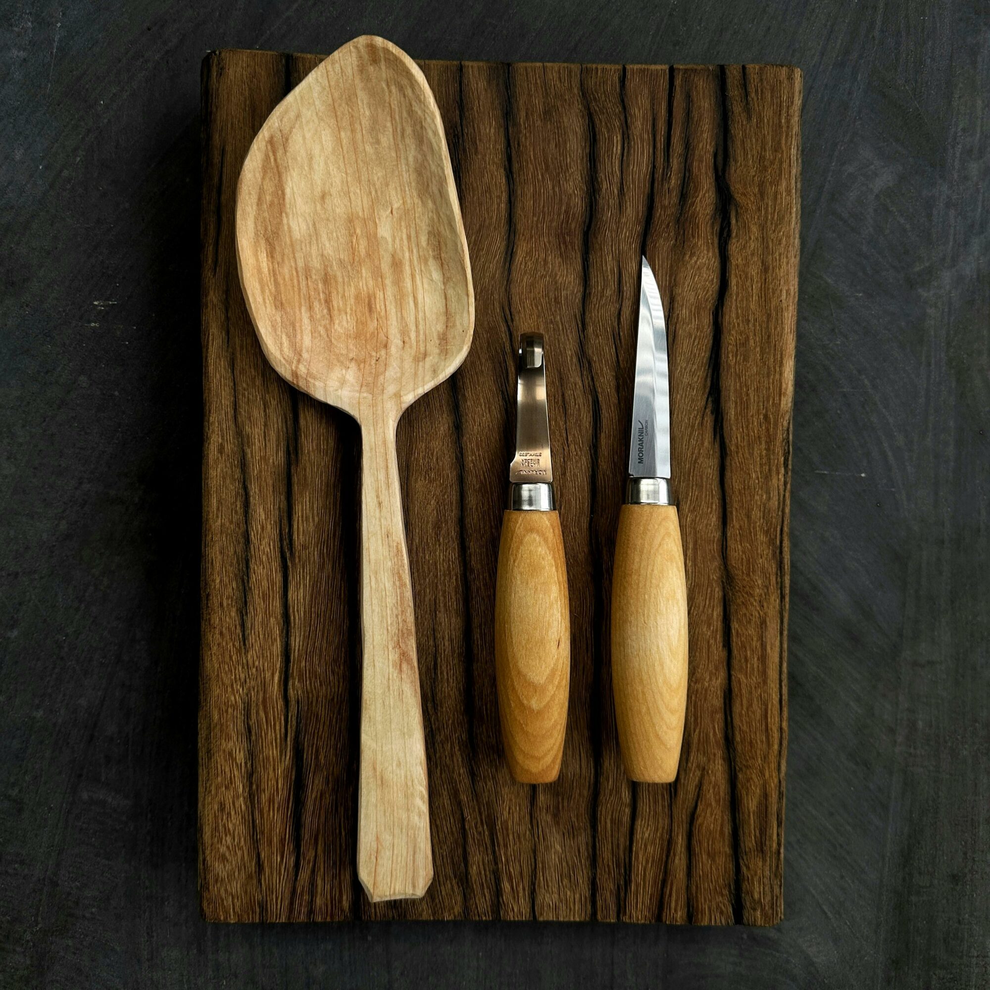 a hand-made wooden spoon with two carving knives