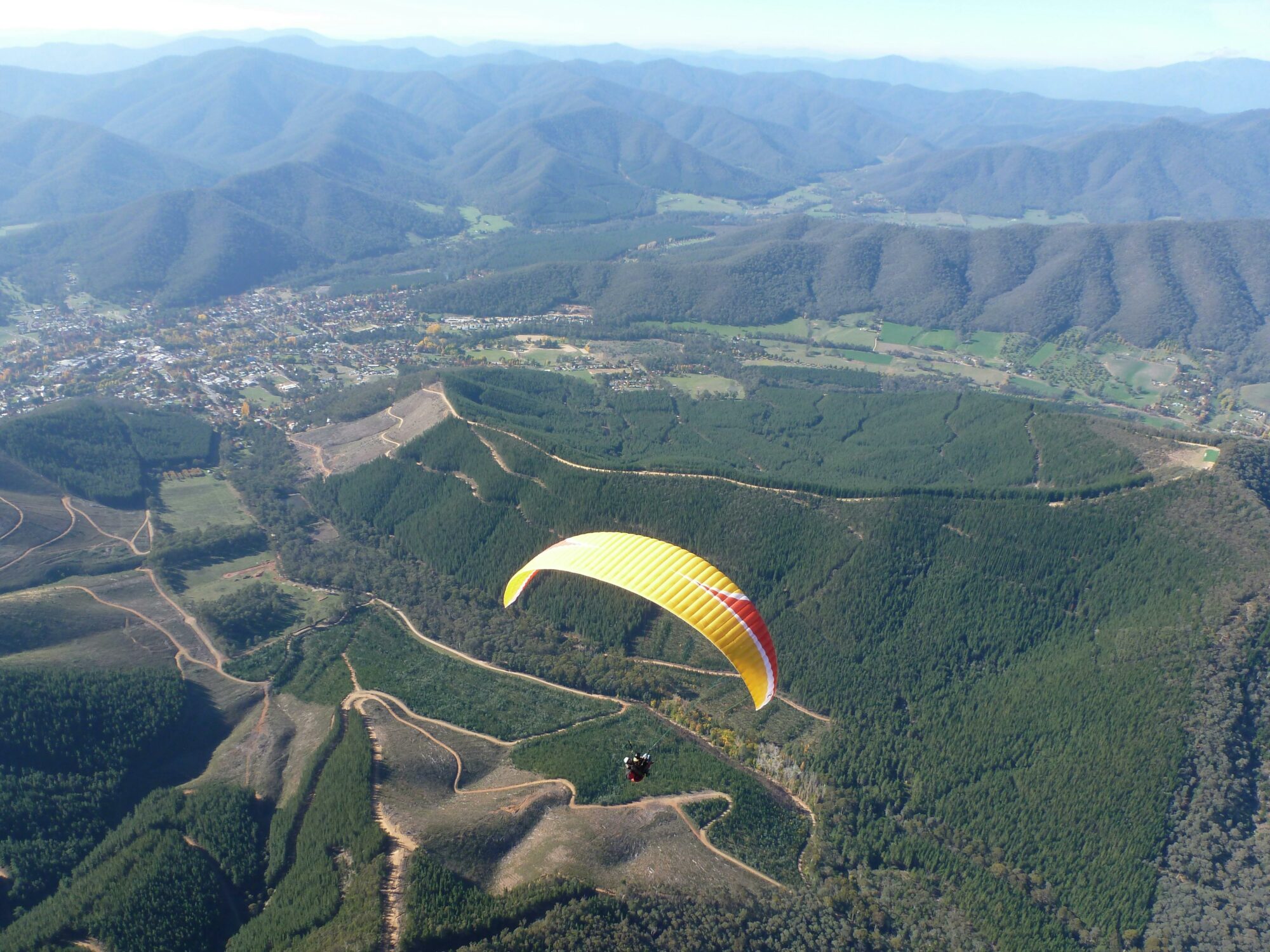 A yellow Paraglider above Bright and it's surrounding mountains