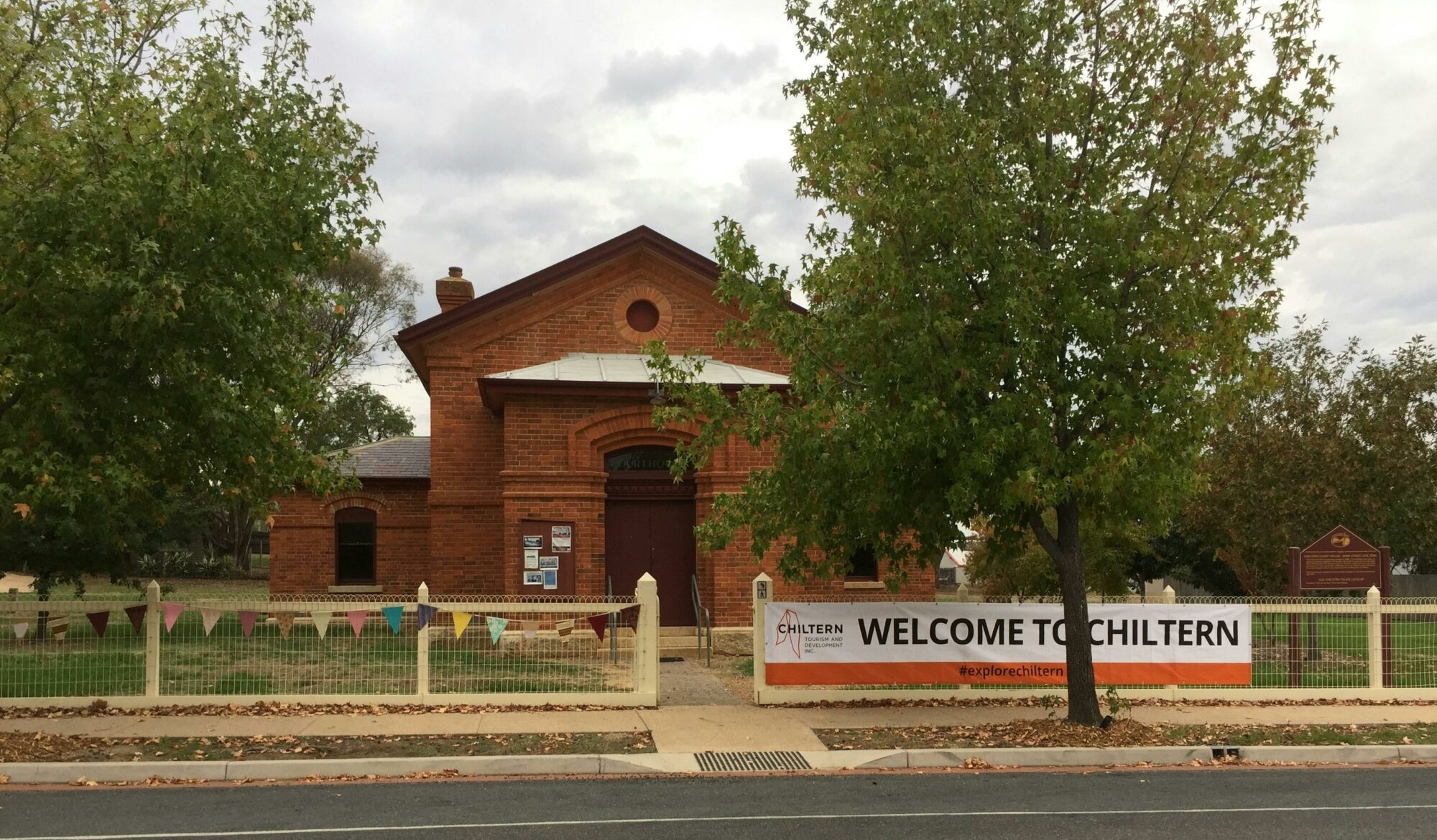 red brick building with trees on naturestrip