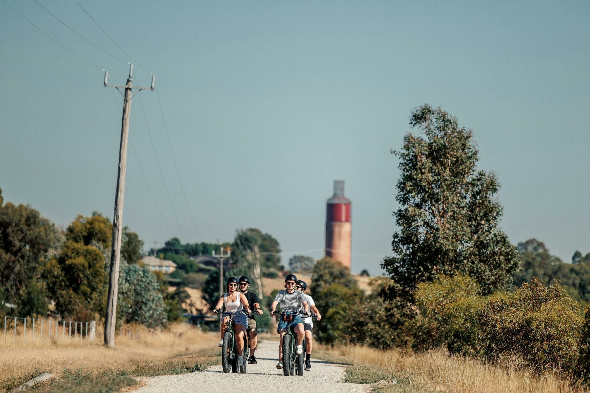 four people riding along Jones Rd with Rutherglen Wine Bottle in background