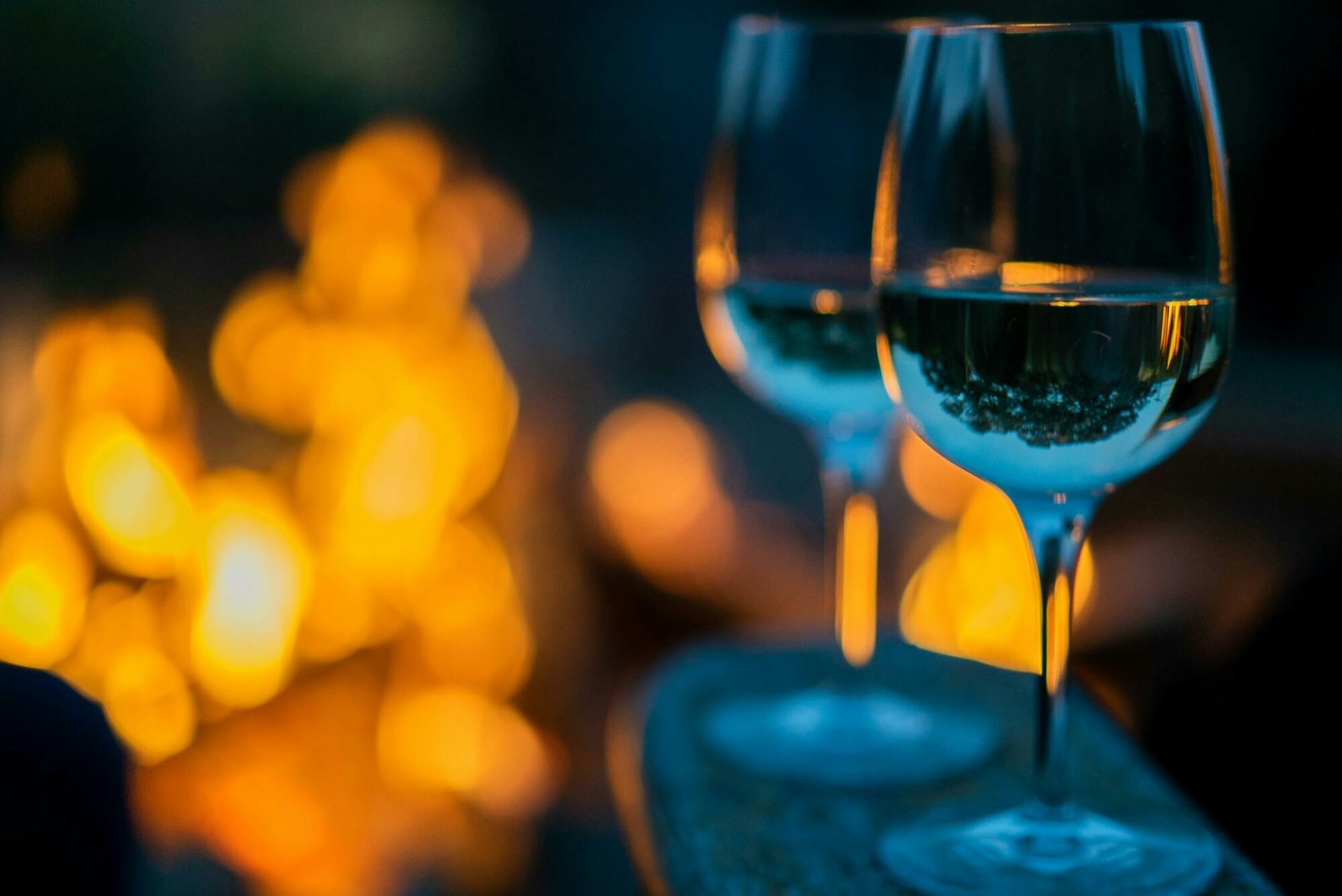 Two glasses of Beechworth Chardonnay by an open fire, glasses in the foreground