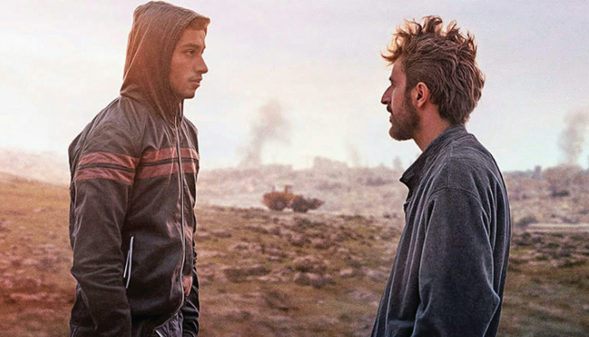 two people facing each other with rubble in the background