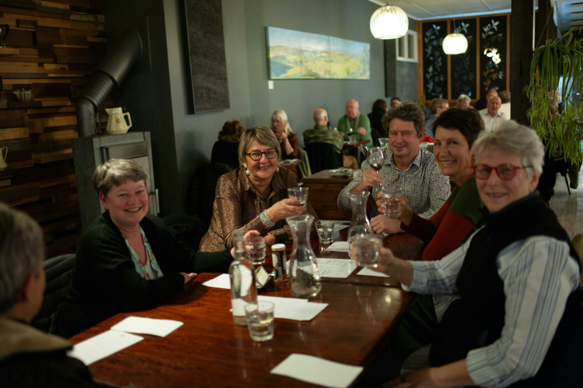 A group of guests, smiling and enjoying dinner at Grant St Grocer