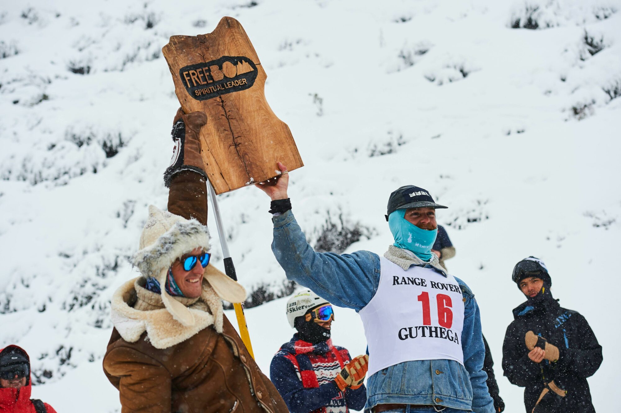 people in winter clothes holding up a sign displaying the text freebom