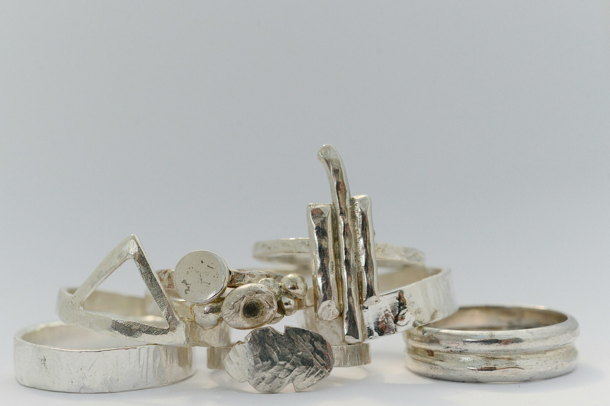 A selection of organic shaped silver rings on a table