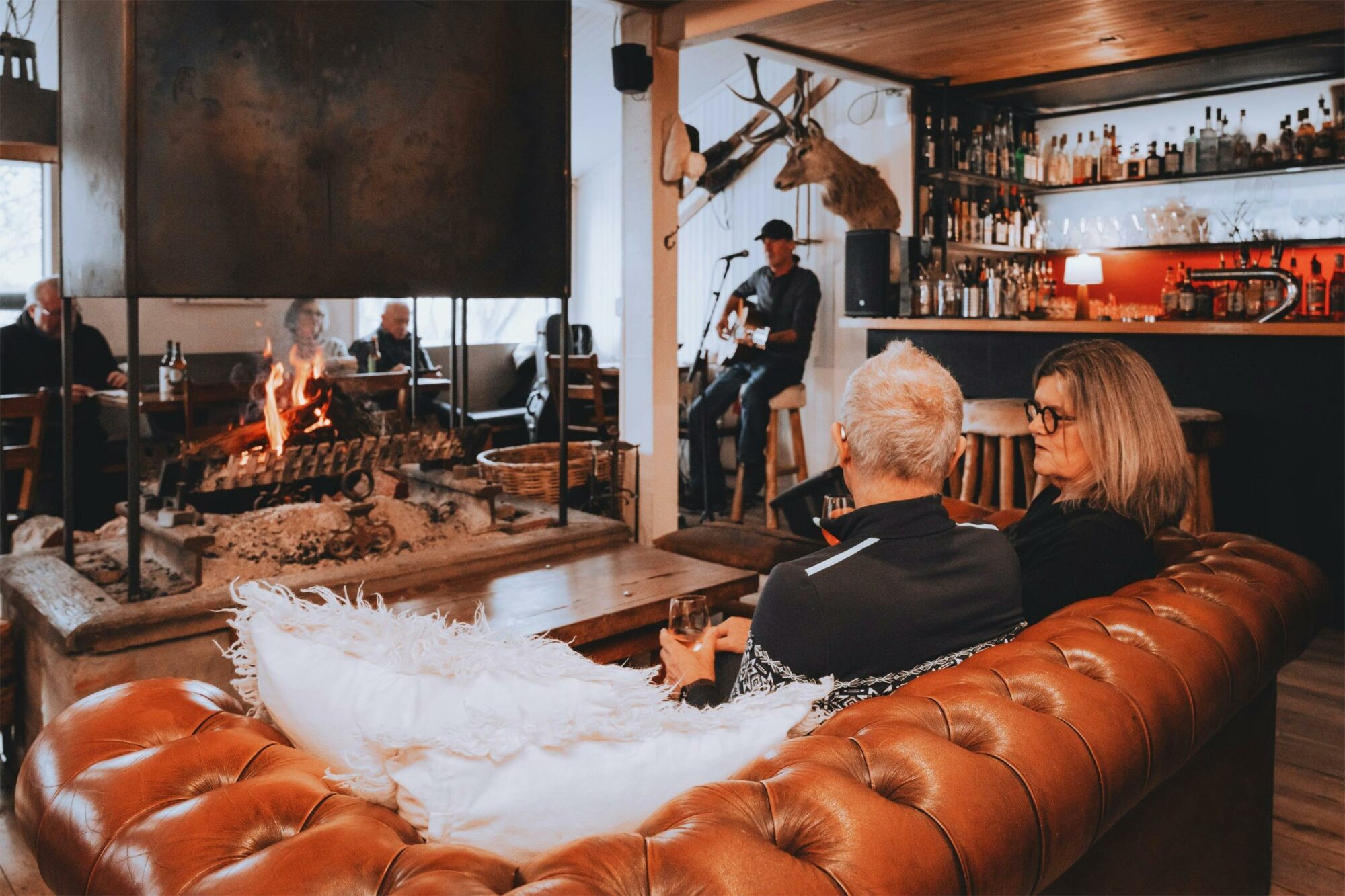 Couple sitting in front of Feathertop’s glowing fireplace with glasses of local wine.