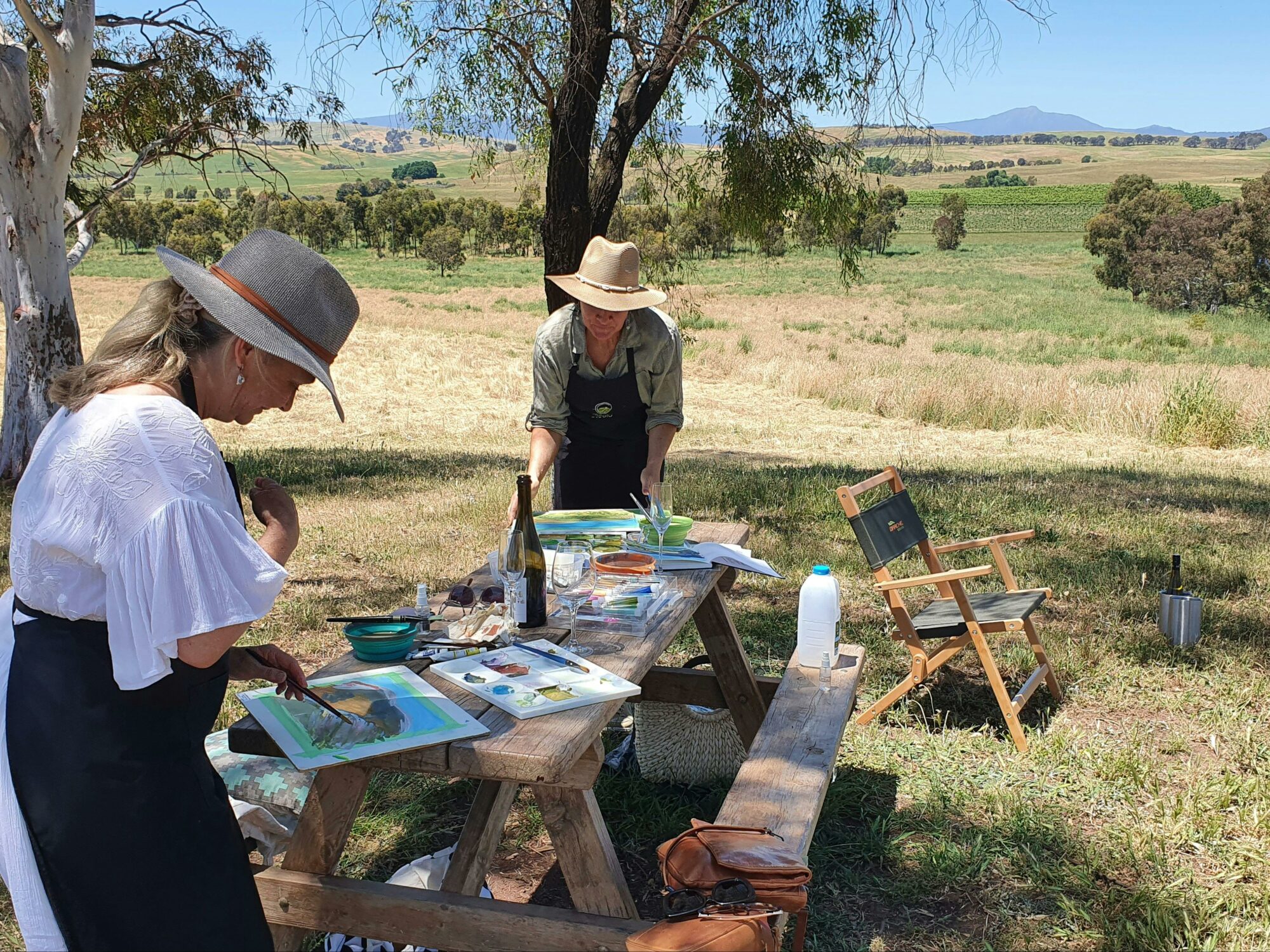 artists painting on a picnic table, mountain views