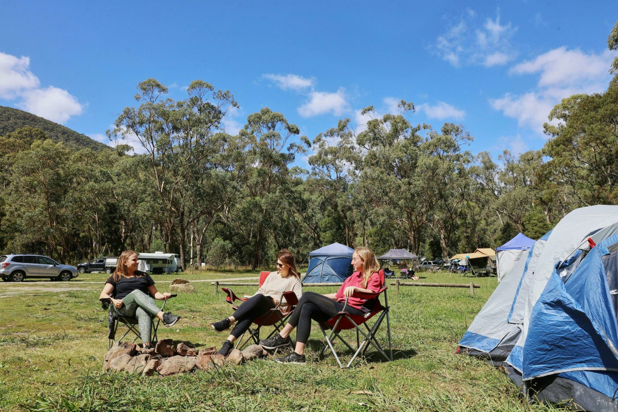 Group of people sitting beside tent in grassy clearing