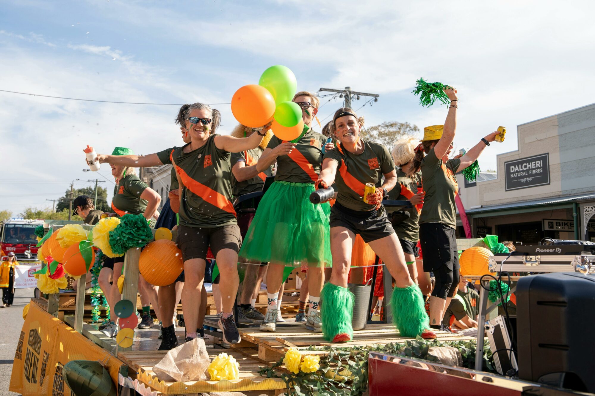festive float  dancers in orange yellow and green for Bridge Road Brewers float