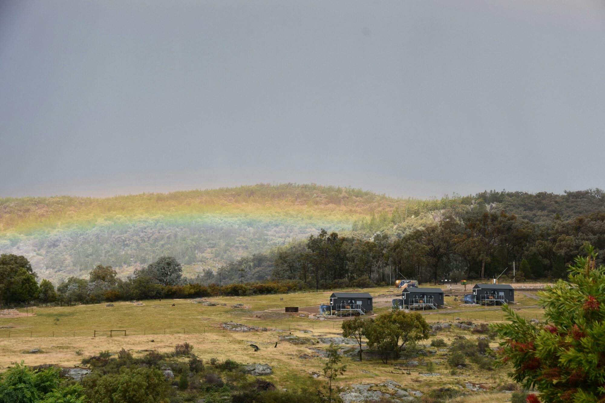 Three tiny homes positioned across rolling rural landscape near Beechworth.
