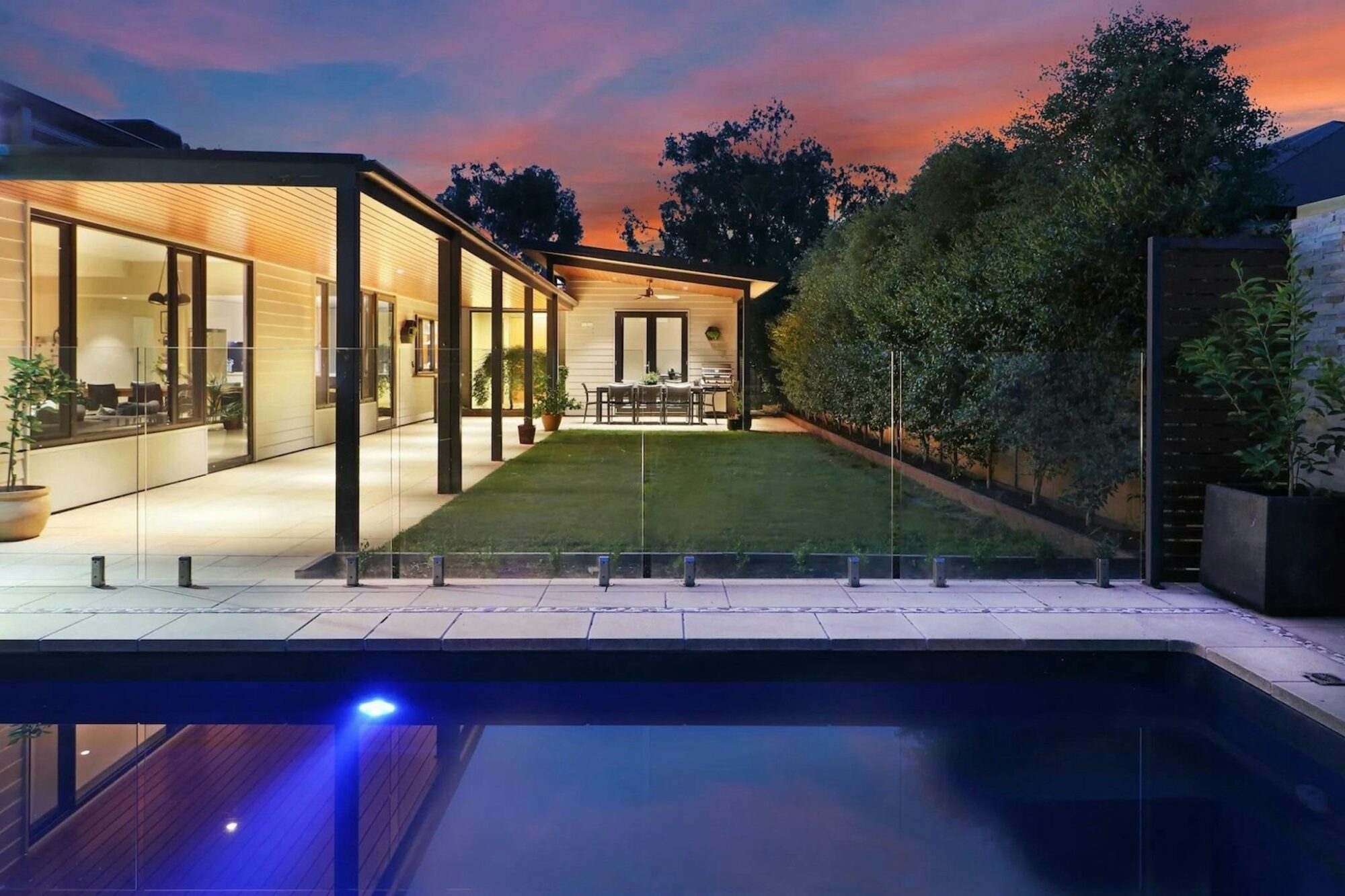 Illuminated swimming pool and outdoor dining at twilight at Banksia House accommodation Mansfield