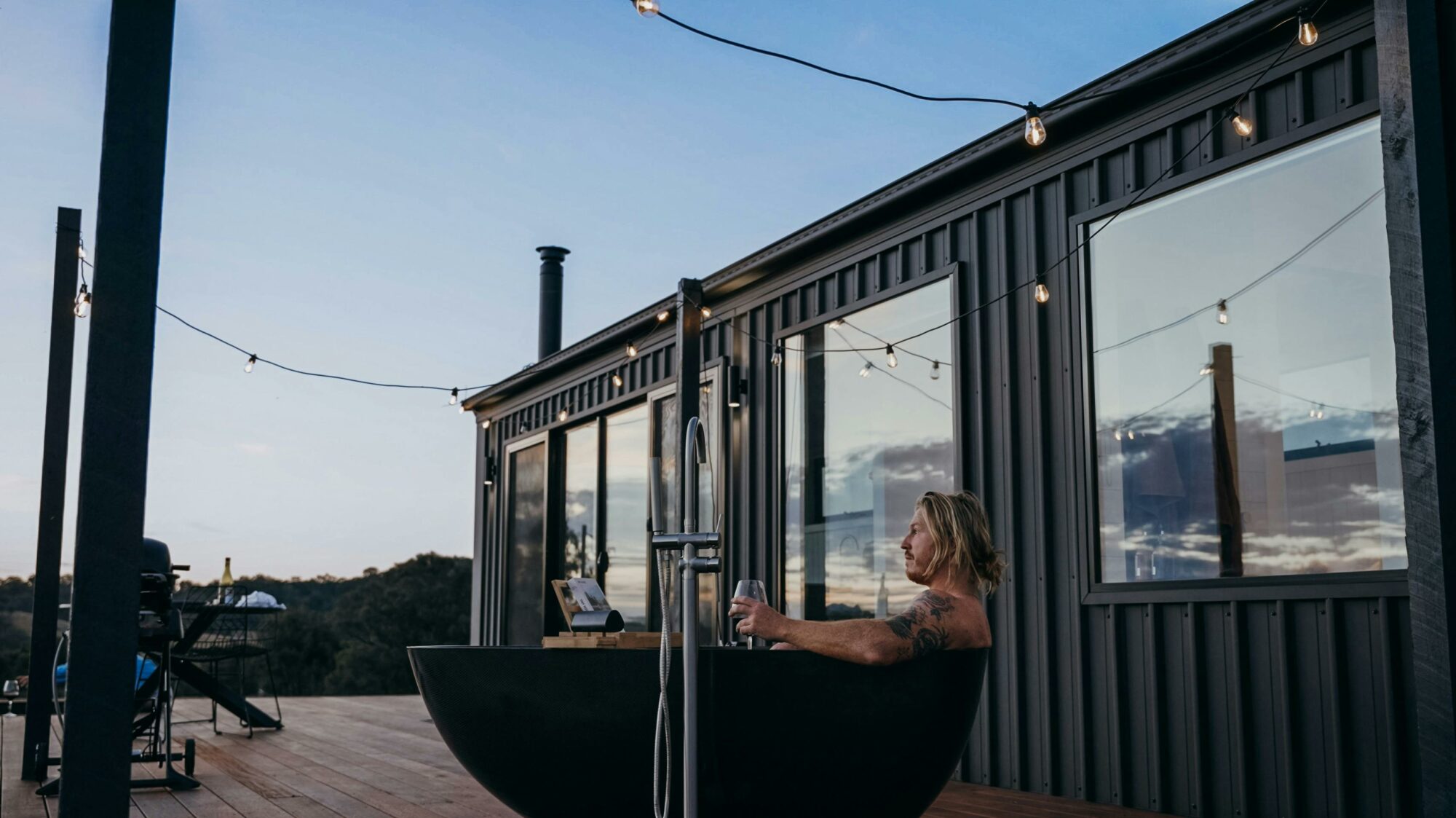 man relaxing in outdoor bath under sunset sky