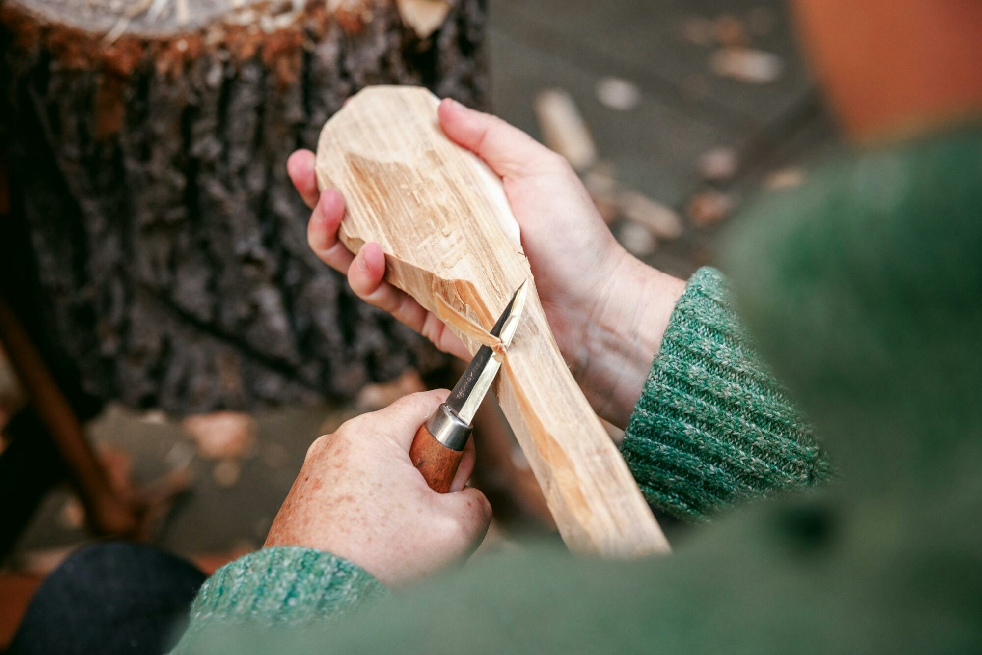 a close up of a person making a hand-made wooden spoon