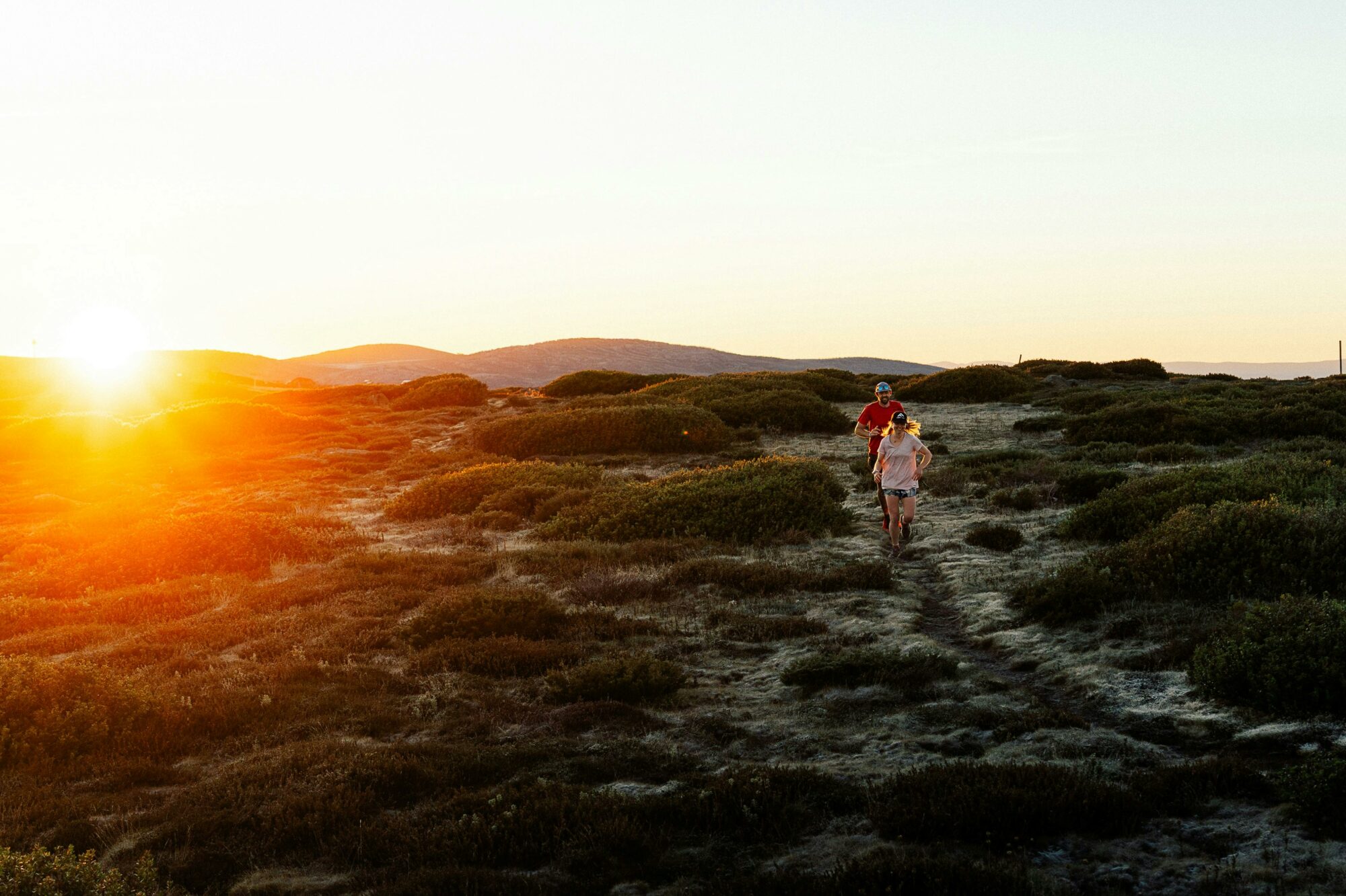 2 runners on an open mountain trail at sunrise