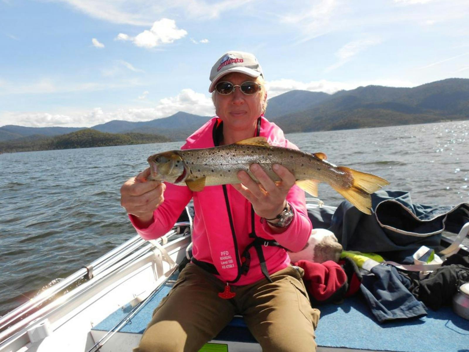 Woman sitting in a boat holding a fish she has just caught