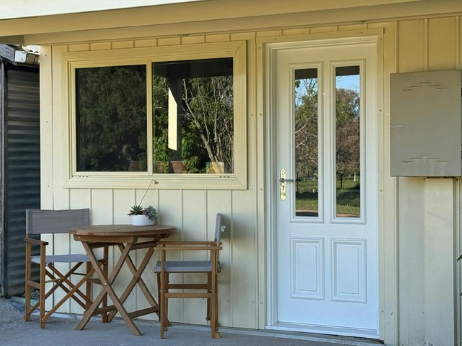 A country home with varandah. Table and 2 chairs by the front door.